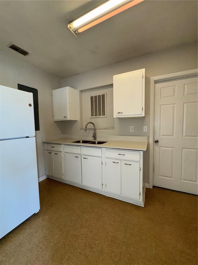 kitchen featuring white fridge, sink, and white cabinets