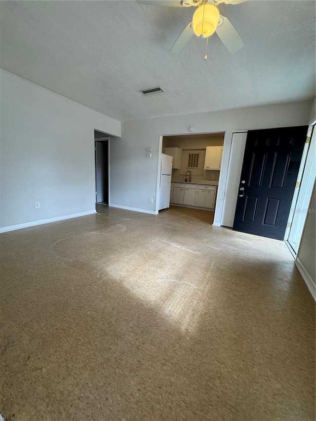 unfurnished living room with ceiling fan and a textured ceiling