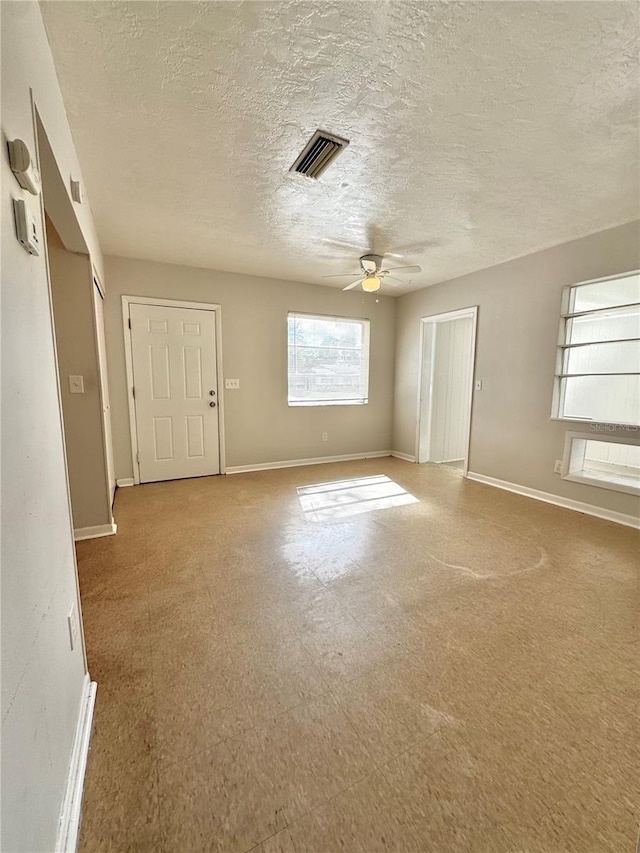 unfurnished room with ceiling fan and a textured ceiling