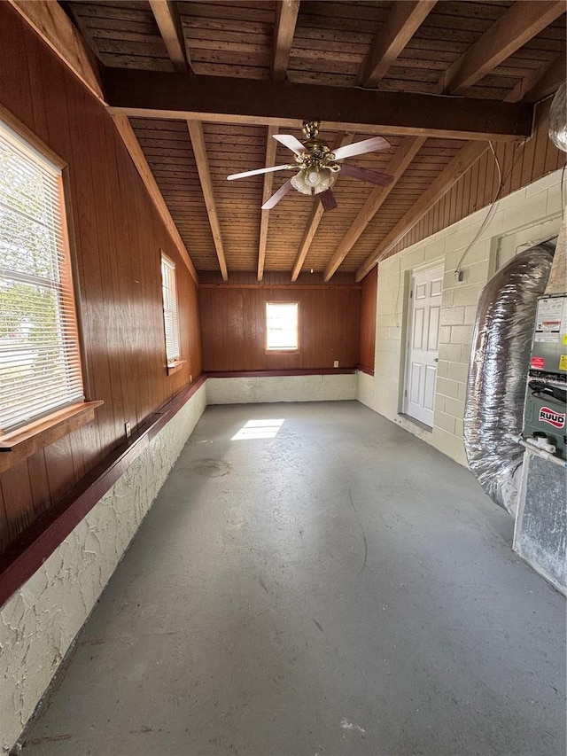 unfurnished room featuring ceiling fan, wooden walls, concrete floors, and vaulted ceiling with beams