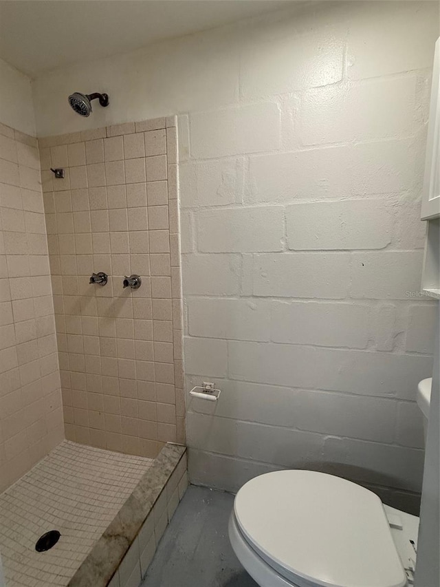 bathroom with a tile shower and toilet