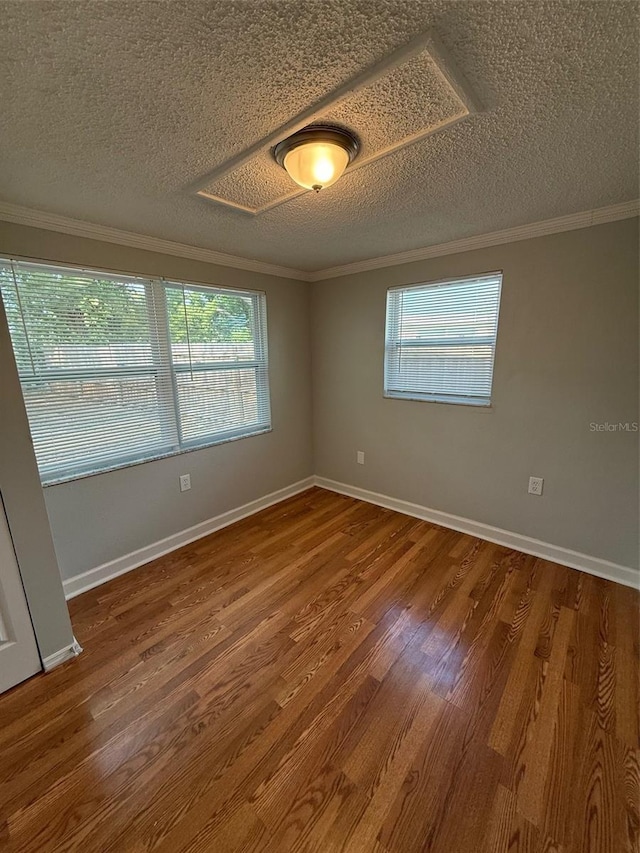 spare room with crown molding, wood-type flooring, and a textured ceiling