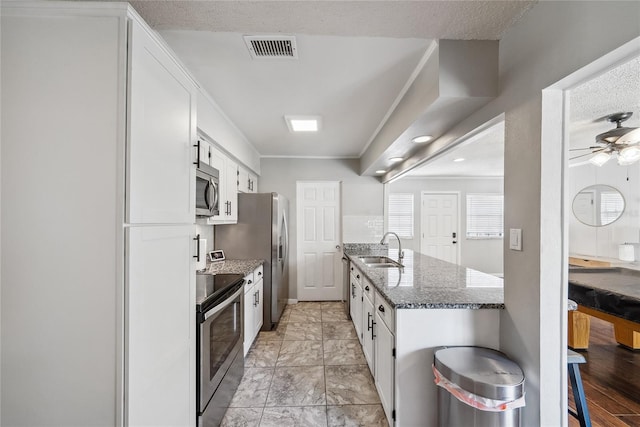 kitchen with sink, stone counters, white cabinetry, appliances with stainless steel finishes, and ornamental molding