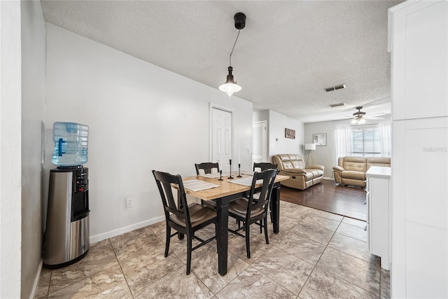 dining space with ceiling fan and a textured ceiling