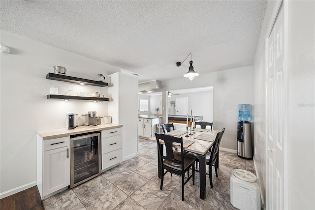 dining space featuring bar, beverage cooler, and a textured ceiling