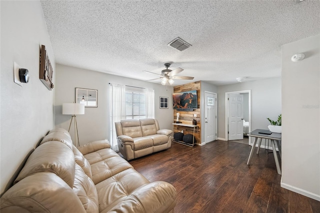 living room with a textured ceiling, dark wood-type flooring, and ceiling fan