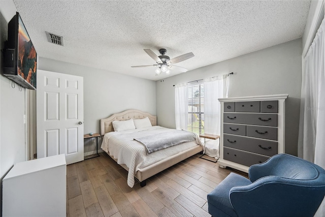 bedroom with dark hardwood / wood-style flooring, a textured ceiling, and ceiling fan