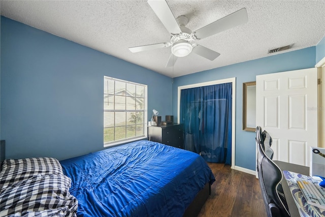 bedroom with dark hardwood / wood-style floors, a textured ceiling, a closet, and ceiling fan