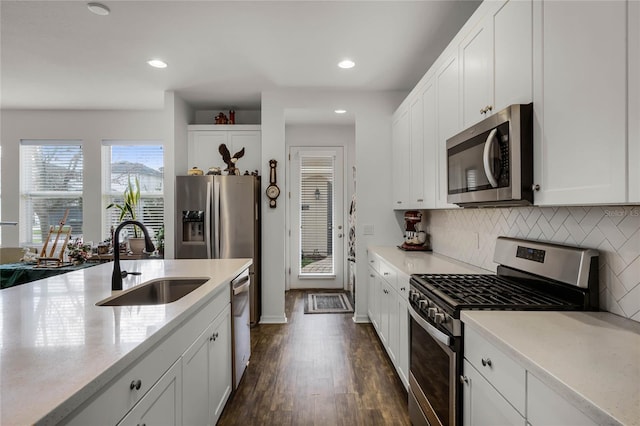 kitchen featuring white cabinets, appliances with stainless steel finishes, light countertops, and a sink