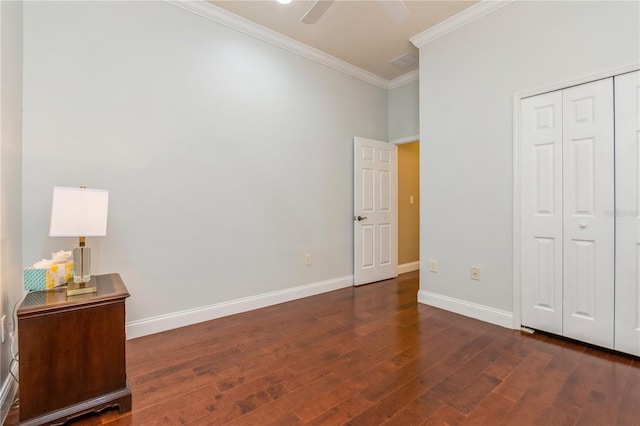 unfurnished bedroom featuring crown molding, dark wood-type flooring, ceiling fan, and a closet