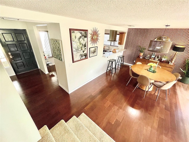 dining area with a textured ceiling, baseboards, and wood finished floors