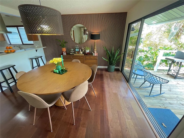 dining space with a textured ceiling, baseboards, and wood finished floors