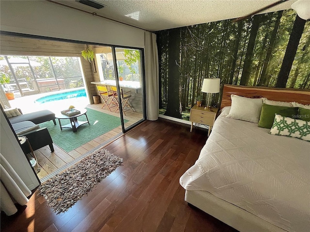 bedroom featuring access to exterior, visible vents, a textured ceiling, and wood finished floors