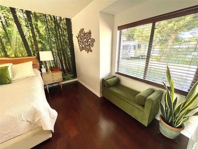 bedroom with a textured ceiling, baseboards, and wood finished floors