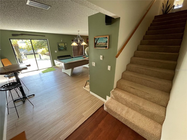 recreation room with a textured ceiling, pool table, wood finished floors, visible vents, and baseboards