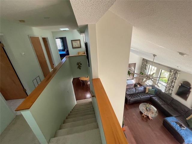 stairway with a textured ceiling, plenty of natural light, wood finished floors, and visible vents