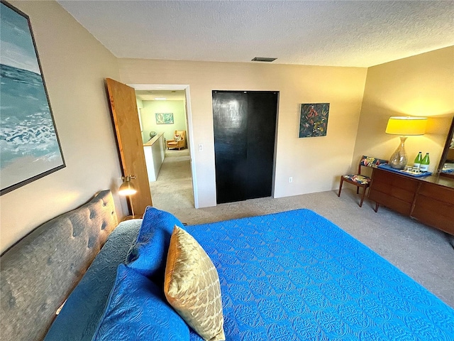 bedroom with visible vents, a textured ceiling, and carpet flooring