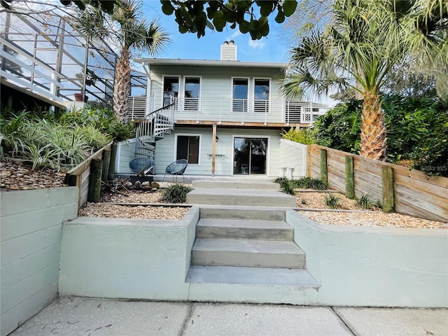 view of front of property featuring a chimney, stairway, and fence