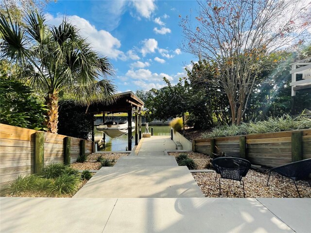 view of community with a dock, boat lift, and fence