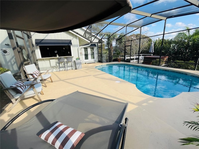 outdoor pool with outdoor dry bar, french doors, a patio area, and a lanai