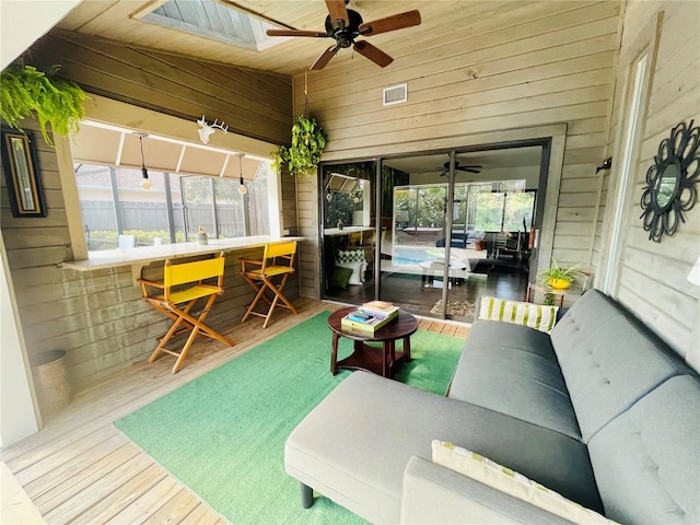 sunroom / solarium featuring vaulted ceiling, plenty of natural light, visible vents, and a ceiling fan