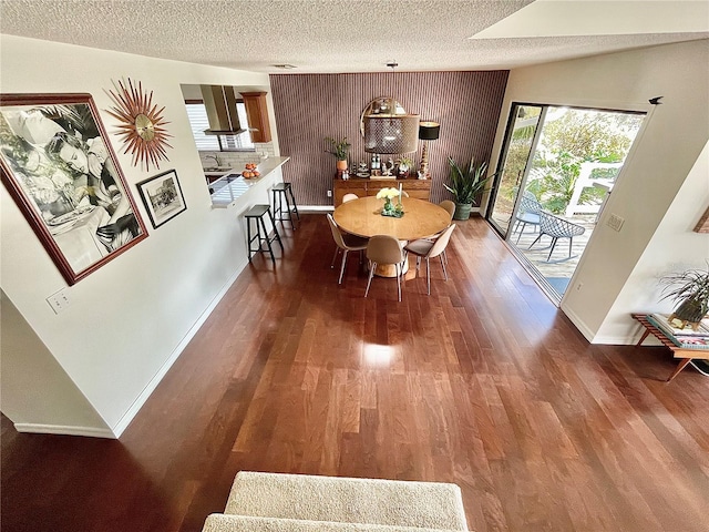 dining area featuring a textured ceiling, baseboards, and wood finished floors