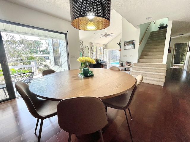 dining room featuring a textured ceiling, wood finished floors, stairway, and lofted ceiling