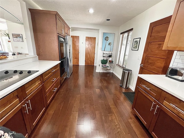 kitchen with dark wood finished floors, light countertops, black appliances, a textured ceiling, and baseboards