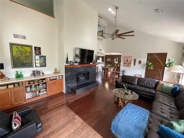 living room featuring dark wood-style floors, a fireplace, a ceiling fan, a textured ceiling, and high vaulted ceiling