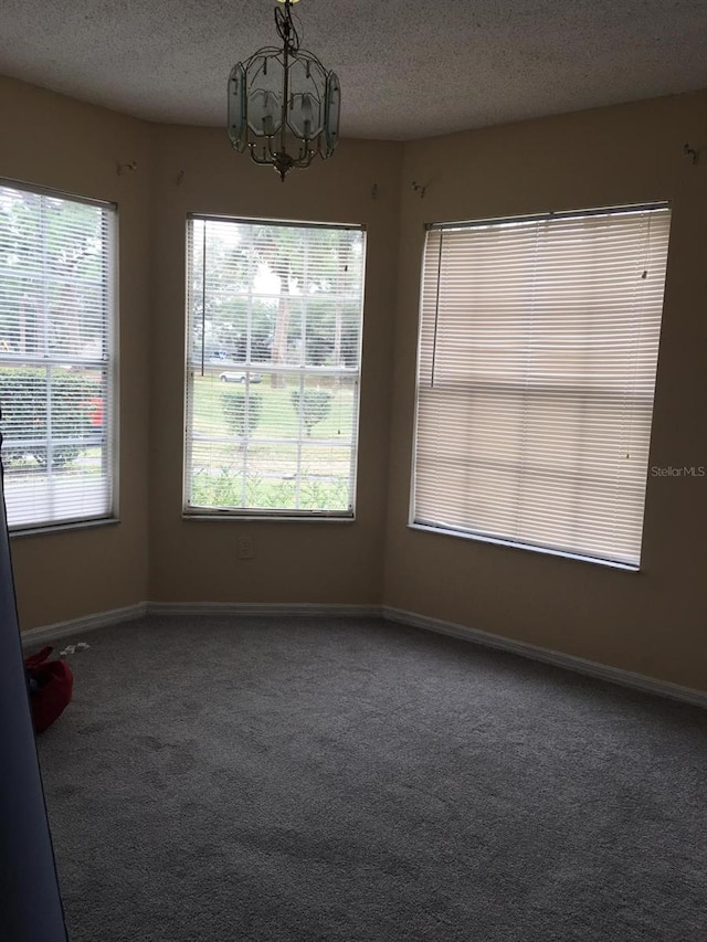 unfurnished dining area with carpet flooring, a chandelier, and a textured ceiling