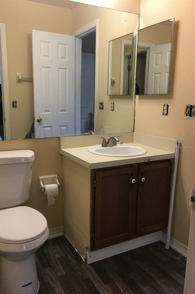 bathroom with toilet, hardwood / wood-style flooring, and vanity