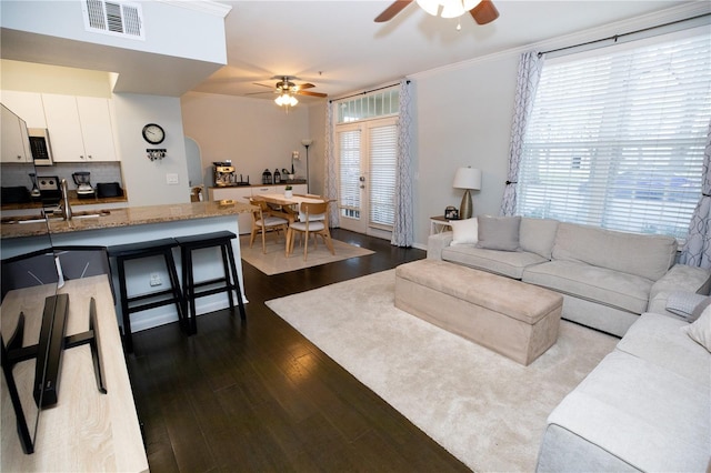 living room with ornamental molding, sink, dark wood-type flooring, and ceiling fan