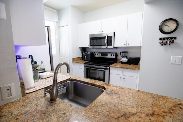 kitchen with white cabinetry, sink, stainless steel appliances, and dark stone countertops