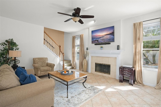 living room featuring ceiling fan, a tile fireplace, and light tile patterned floors