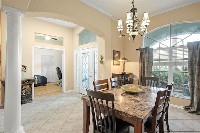 tiled dining area featuring a towering ceiling, ornamental molding, a chandelier, and ornate columns