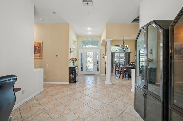 entrance foyer featuring ornate columns, light tile patterned floors, and a chandelier