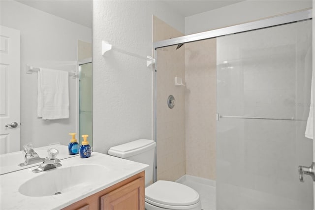 bathroom featuring vanity, toilet, and a shower with shower door