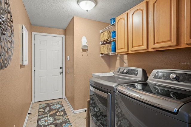 clothes washing area with cabinets, separate washer and dryer, light tile patterned floors, and a textured ceiling