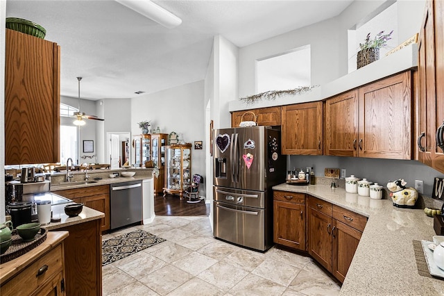 kitchen featuring stainless steel appliances, light stone counters, a towering ceiling, pendant lighting, and sink