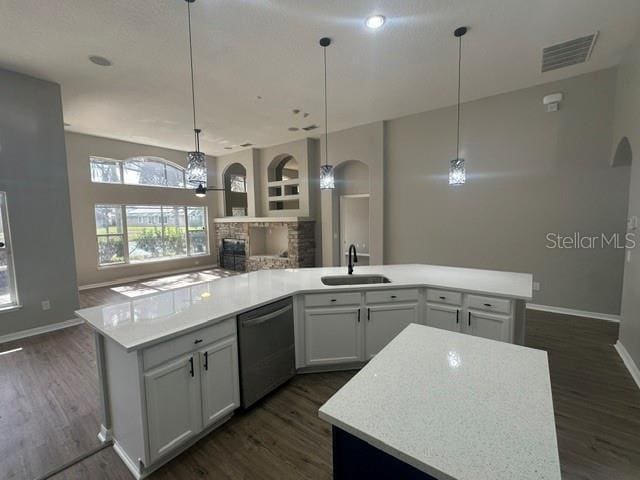 kitchen with open floor plan, light countertops, a sink, and a kitchen island with sink