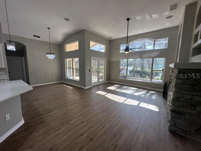 unfurnished living room featuring high vaulted ceiling, dark wood-style flooring, a wealth of natural light, and baseboards