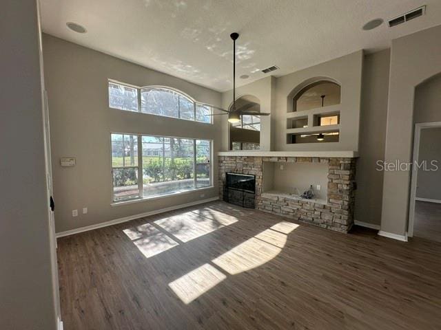 unfurnished living room with dark wood-style floors, a fireplace, baseboards, and built in features