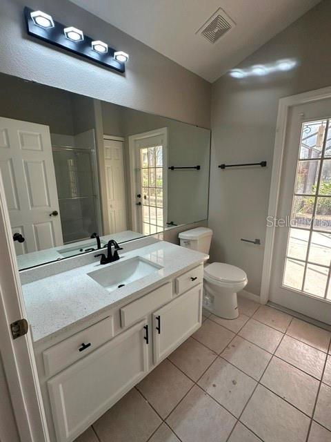 bathroom featuring visible vents, vaulted ceiling, a shower stall, vanity, and tile patterned floors