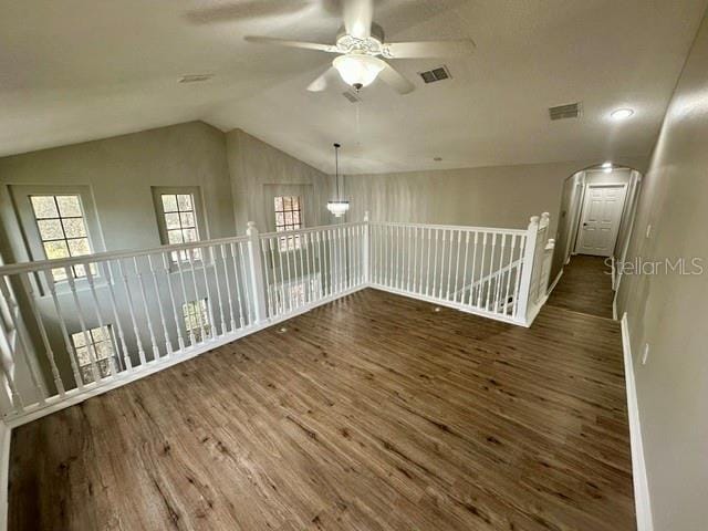 unfurnished room with ceiling fan, vaulted ceiling, visible vents, and dark wood finished floors