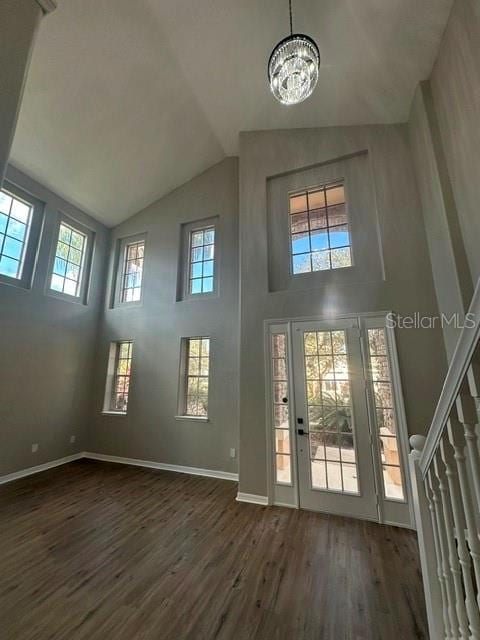 foyer entrance featuring stairway, an inviting chandelier, dark wood finished floors, and baseboards