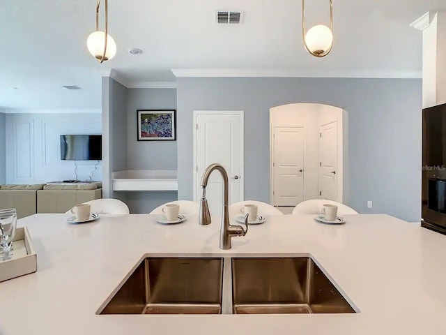 kitchen with sink, ornamental molding, and hanging light fixtures