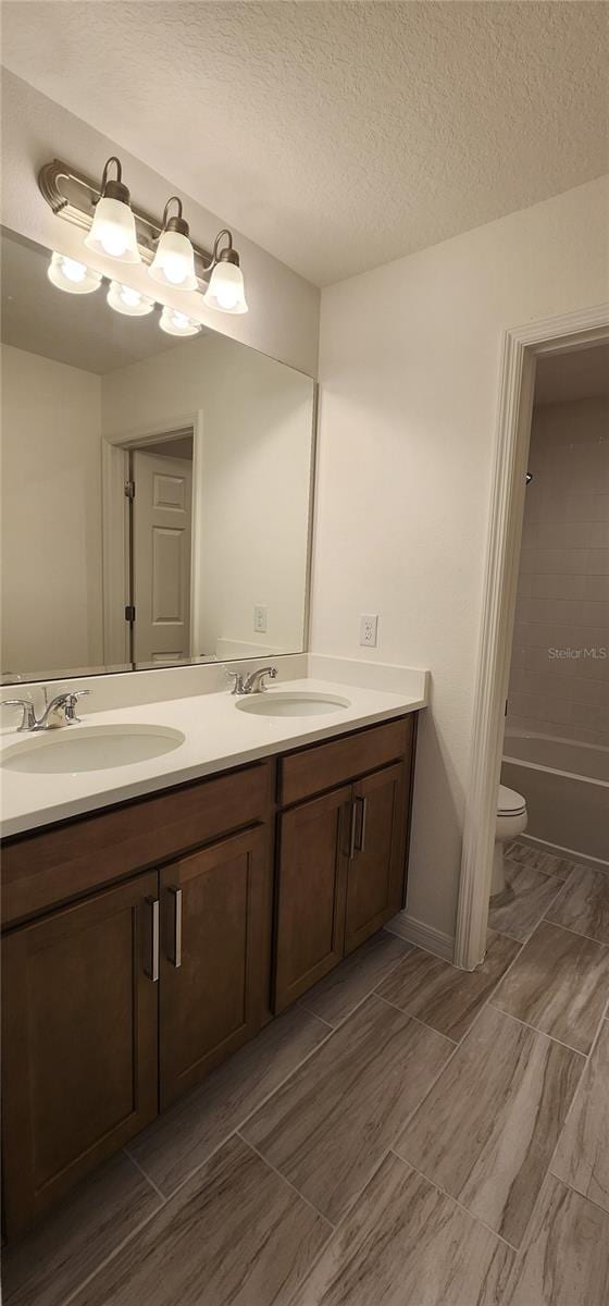 full bathroom featuring vanity, toilet, shower / bath combination, and a textured ceiling