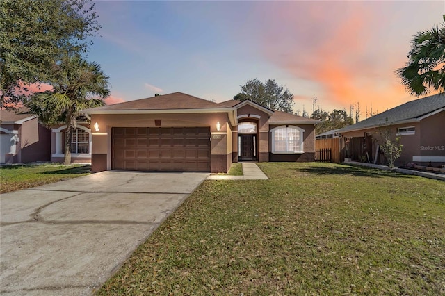 ranch-style house featuring driveway, a lawn, an attached garage, and stucco siding