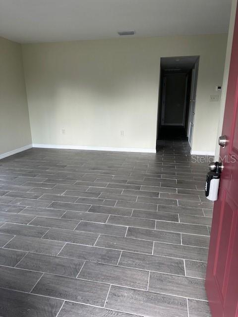 spare room with baseboards, visible vents, and wood tiled floor