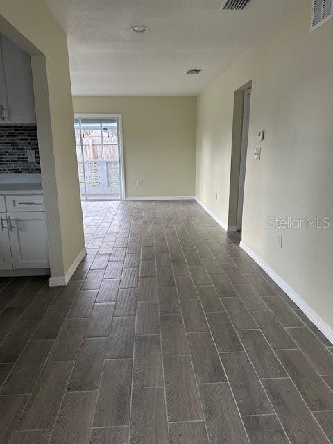 empty room with wood finish floors, visible vents, and baseboards